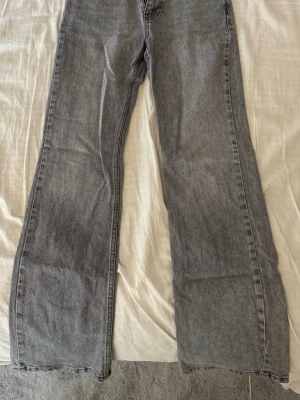 Gråa utsvängda jeans - Säljer ett par gråa jeans med utsvängda ben.