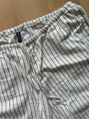 Randiga linnebyxor - Aldrig använda - supersköna, löst sittande byxor från H&M Divided i vitt/off-white med svarta ränder. De har en avslappnad passform med vida ben, resår samt dragsko i midjan och fickor i sidorna plus en bakficka. Medelhög midja✨