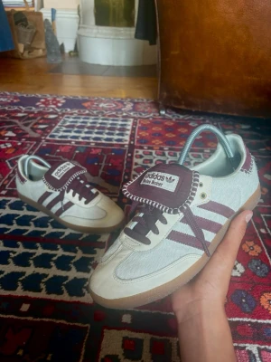 Adidas Wales Bonner sneakers beige/vinröd - Säljer några av de mest eftertraktade samt fetaste skorna på marknaden, Wales Bonner creme&red adidas sneakers, passar storlek 42, hör av dig vid fundering. Jag fraktar alltid inom 24 timmar! Om jag inte är på semester.  ‼️Helt nya!!  Pris kan diskuteras vid snabb affär😊