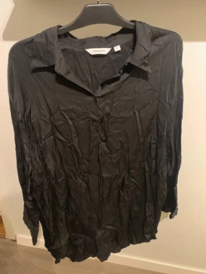 Svart långärmad skjorta Kappahl - Svart skjorta från Kappahl med klassisk krage och knäppning framtill. Långärmad modell i ett lätt och tunt tyg som ger en avslappnad känsla. Perfekt att styla till jeans eller kjol.