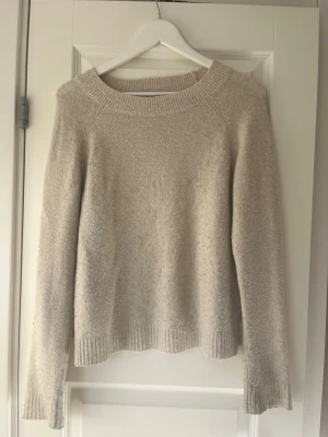 Stickad tröja - Mysig vit/beige stickad tröja med rund halsringning och långa ärmar. Tröjan har ribbstickade muddar vid ärmslut och nederkant.  Har ett hål på ena ärmen, men kan säkert gå att sy ihop! Tyvärr är jag inte erfaren i att sy igen hål på stickat. Finns även en liten lös tråd på ryggen. Säljer då den inte passar mig💗