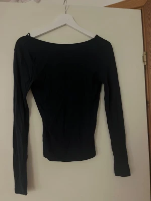 Marinblå långärmad backless topp - En enkel marinblå långärmad topp med bred, rund ringning bak. Modellen är tight och passar perfekt till jeans eller kjol. Tillverkad i mjukt material.
