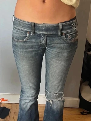 Blåa diesel jeans med slitningar - Snygga blåa jeans med slitningar på knäna och dubbla knappar i midjan. Midjemått är 74cm (men passar också 80cm) 
