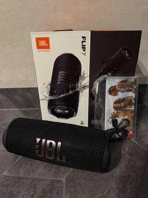 JBL Flip 7 bluetooth högtalare svart - Säljer en helt ny JBL Flip 7 bärbar högtalare i svart. Den har en cylinderformad design och är perfekt för att ta med sig överallt tack vare sin kompakta storlek och vattentåliga konstruktion. Den låter högt och är i mycket fint skick och kvalitet