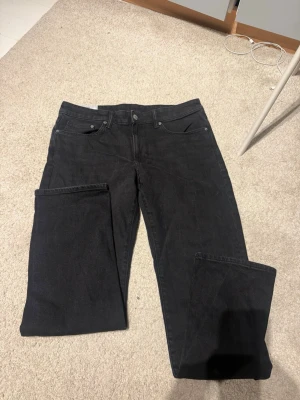 Svarta raka jeans - Säljer ett par svarta jeans med rak passform och klassisk femficksdesign. Jeansen har normal midja och är tillverkade i ett mjukt denimtyg. Perfekta för dig som gillar en enkel och stilren look.