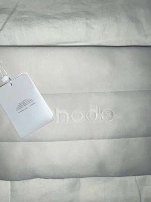 Beige quiltad clutch från rhode - Säljer en beige quiltad clutch från rhode med dragkedja upptill och diskret logga på framsidan. Väskan har en mjuk, vadderad känsla och stilren design som passar perfekt till alla tillfällen. Praktisk storlek för det viktigaste.