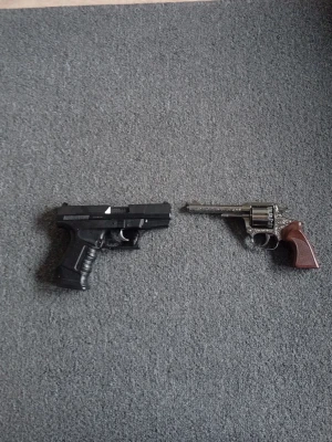 Två leksakspistoler för maskerad - Säljer två leksakspistoler perfekta till maskerad eller cosplay. Ena pistolen är svart med realistisk design och den andra är en silverfärgad revolver med brunt handtag och orange markering i mynningen. Båda är tillverkade i plast.