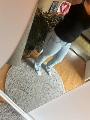 Ljusblå raka jeans med hög midja - Säljer ett par ljusblå jeans med raka ben och hög midja. Jeansen har klassiska fem fickor och en snygg tvättad look. Passar perfekt till en avslappnad stil och är gjorda i ett mjukt denimtyg som sitter bekvämt.