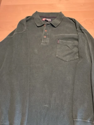 Grön långärmad henley från Chaps/ralph lauren  - Mörkgrön långärmad henley från Chaps Ralph Lauren i 100% bomull. Skjortan har klassisk krage, tre knappar framtill och en bröstficka med liten logga. Pris kan diskuteras 