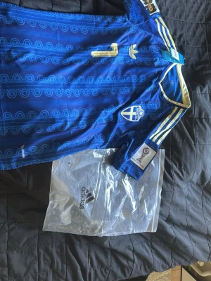 Blå Sverige fotbollströja Adidas - Säljer en blå äkta Sverige fotbollströja från Adidas med guldiga detaljer och mönster. Tröjan har nummer 7 och namnet 'Bergvall' på ryggen, samt Sveriges landslagsemblem på bröstet. Klassiska Adidas-ränder på axlarna och officiell märkning på ärmen. Köpt för 1749Tröjan är storlek S. Orginal tags fås med. 
