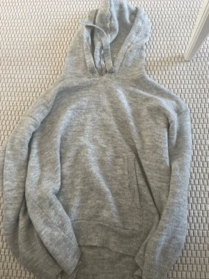 Grå hoodie från Lefties - Mysig grå hoodie från Lefties i storlek S. Den har en klassisk huva, ribbade muddar och en känguruficka framtill. Perfekt för en chill och avslappnad stil. Materialet är mjukt och stickat, vilket gör den extra skön att ha på sig.