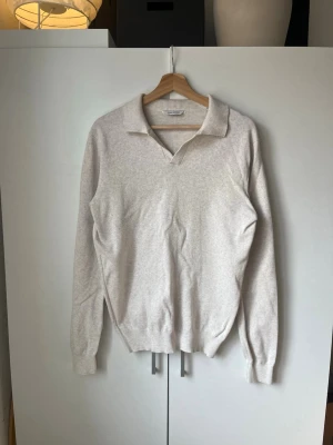 Beige långärmad tröja - Stilren beige långärmad tröja med klassisk krage. Tröjan har ribbade muddar vid ärmslut och midja, vilket ger en snygg passform. Super bra skick