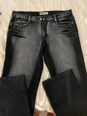 Svarta bootcut jeans  - Snygga svarta bootcut jeans med slitningar och ljusare tvätt framtill. Jeansen har klassisk femficksdesign, silverfärgade nitar och markerade sömmar. Perfekta för dig som gillar en cool och avslappnad stil.