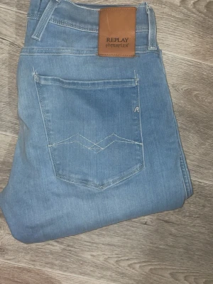 Ljusblå Replay Hyperflex jeans - Säljer ett par ljusblå jeans från Replay Hyperflex med klassisk femficksdesign och raka ben. Jeansen har en snygg tvätt och är tillverkade i stretchigt material för extra komfort. Perfekta för en avslappnad och trendig look. Skickar samma dag vid köp, passar även 30