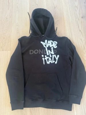 Svart hoodie från Dondup - Svart hoodie från Dondup med vit graffiti-text 'MADE IN ITALY' på bröstet. Klassisk känguruficka framtill, ribbade muddar och justerbar huva. Köpt från Dondup affär i Italien för 210€. Storlek: L (passar även M) | Skick 9/10 | Meddela vid eventuella frågor! Allt gott!