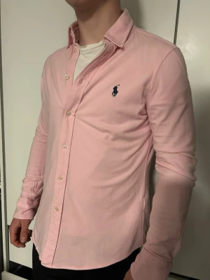 Ralph Lauren skjorta - Säljer en rosa skjorta från Ralph Lauren med mörkblå logga på bröstet. Inga defekter eller fläckar och väldigt bra skick, pris kan diskuteras vid snabb affär🙂