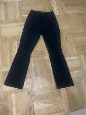 Svarta kostymbyxor med utsvängda ben - Snygga svarta kostymbyxor med utsvängda ben. Mycket bra skick. De är midwaist nästan högmidjade. 