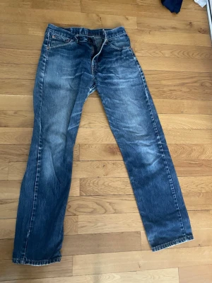 Levi's blå raka jeans - Klassiska blå jeans från Levi's med raka ben och snyggt slitna detaljer. Jeansen har fem fickor, dragkedja och knapp i midjan samt tydliga sömmar. Perfekta för en avslappnad och trendig look. De är 33/34 men passar mycket mindre för de är äldre och det är inte 501 