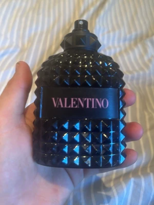 Valentino parfym svart nitat flaska. Använd några gånger - Snygg parfym från Valentino i en cool svart flaska med nitat mönster och rosa text. Flaskan är robust och har en lyxig känsla, perfekt att ha framme på hyllan. Materialet är glas och designen sticker verkligen ut.