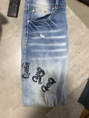 Amlri Jeans - Ett par ljus blåa Amlri jeans i storlek W28