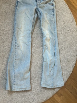 Ljusblå bootcut jeans True Religion - Säljer ett par ljusblå bootcut jeans från True Religion med ikoniska broderade fickor bak och knappdetaljer. Jeansen har en klassisk femficksmodell och är tillverkade i denim med en tvättad look. Perfekta för dig som gillar retrovibbar och snygga detaljer. Jag är 160 o dom kanske är typ 3 cm korta