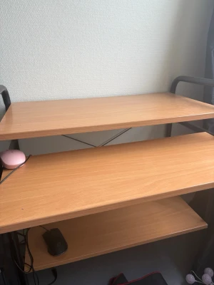 Skrivbord med tre hyllplan - Säljer ett skrivbord i träimitation med tre hyllplan och svarta metallben. Perfekt för dator, böcker eller annan förvaring. Bordet har en enkel och modern design som passar i de flesta rum.