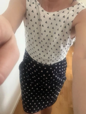 STOCKH LM  - Snygg ärmlös klänning från stockh lm  med vit överdel och svart kjol, båda delarna har ett triangelformat mönster. Klänningen har rund halsringning och markerad midja. Perfekt för dig som gillar grafiska prints och enkel stil.