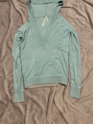 Ljusblå hoodie med v-ringning - Snygg ljusblå hoodie från cubus med v-ringning och stor huva. Hoodien har en känguruficka framtill och ribbade muddar vid ärmslut och nederkant. Perfekt för en chill och avslappnad stil.