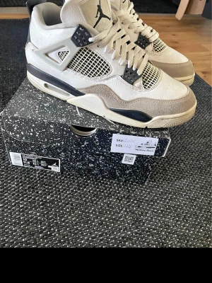 Air Jordan 4 Military Black sneakers - Säljer ett par Air Jordan 4 Military Black sneakers i vitt, svart och grått. De är helt äkta och har kvitto från merchsweden med serienummer på. Använts ett par gånger men de är ändå i bra skick. Lite creasing i hälen men det är inget man lägger märke till.