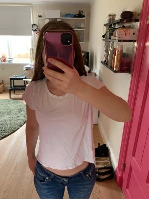 Vit croppad t-shirt i bomull - En enkel och fräsch vit t-shirt med croppad passform. T-shirten har korta ärmar och rund halsringning, tillverkad i mjuk bomull som känns skön mot huden. Perfekt till jeans eller shorts för en avslappnad look.