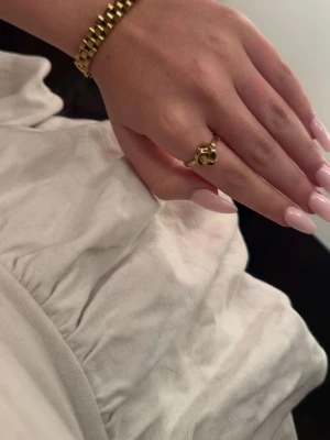 Guldfärgad ring med knutdetalj - Stilren guldfärgad ring med en unik knutdetalj framtill. Ringen har en blank finish och är enkel men ändå iögonfallande. Perfekt för dig som gillar trendiga accessoarer med en twist. Levereras i en snygg ask. Slutsåld💕