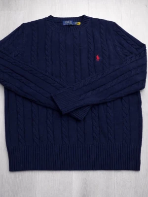 Blue Ralph Lauren sweater  - Stilren och tidlös marinblå kabelstickad tröja från klassiska Polo Ralph Lauren. Den ikoniska röda loggan på bröstet ger en exklusiv touch medan den mjuka stickningen gör den både bekväm och elegant – perfekt för både vardag och uppklätt. ✨🧥