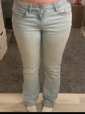 Ljusblå bootcut jeans  - Säljer ett par ljusblå jeans med rak passform och klassisk femficksdesign. Jeansen har normal midja och är tillverkade i ett mjukt denimtyg. Perfekta för en avslappnad och trendig look. Dom har ett litet hål i skrevet. VÅGA BUDA