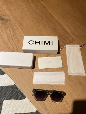  CHIMI 004 gray - Snygga solglasögon från CHIMI i grå färg med klassisk, stilren design. Kommer med originalförpackning, hårt fodral och mjukt fodral. Perfekta för att lyfta din look med en modern touch.