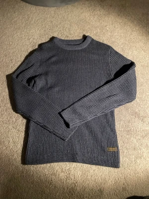 Marinblå  ribbstickad tröja - Snygg marinblå ribbstickad tröja med rund hals och långa ärmar. Tröjan har en diskret patch nertill på ena sidan och är tillverkad i ett mjukt, stretchigt material som sitter skönt på kroppen. Perfekt för lager på lager under kyliga dagar.