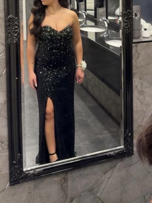 Svart paljettklänning  - Snygg svart långklänning med glittriga paljetter och en djup slits framtill.  Passar s/m. 