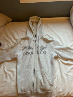 Grå zip hoodie från Bvaldi - Säljer en ljusgrå hoodie från Bvaldi med dragkedja, huva och fickor.Perfekt för dig som vill sticka ut med en unik och bekväm hoodie.  Nypris cirka 1100kr, andvänd ungefär 3 gånger. Inga defekter. Tvivla inte att höra av dig vid minsta funderingar 