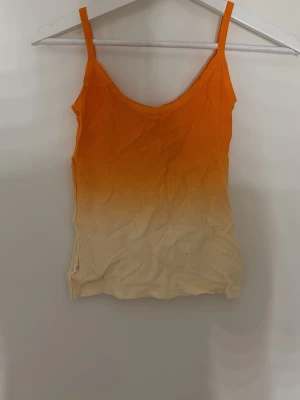 Ombre orange och beige linnetopp - Snygg linnetopp med smala axelband i en ombre färgskala från orange upptill till beige nedtill. Perfekt för varma dagar och enkel att matcha med jeans eller kjol. Tunn och mjuk känsla . Står ej storlek men skulle säga den passar som storlek small. Väldigt elastisk