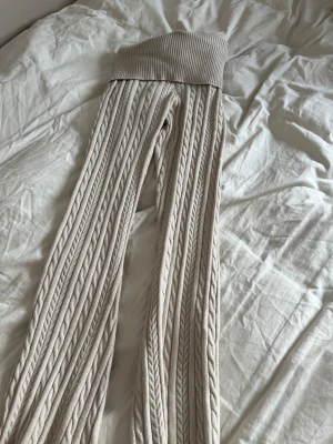 Beige kabelstickade leggings Gina Tricot - Supersnygga beige leggings från Gina Tricot med kabelstickat mönster och bred ribbad midja. Perfekta för dig som vill ha både stil och komfort. Materialet är mjukt och stretchigt, vilket gör dem riktigt sköna att ha på sig.