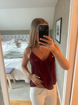 Vinrött snyggt linne från Gina tricot  - En sjukt snyggt linne med volang i ett ”strävare” tyg från Gina tricot i storlek XS! Passar till jeans eller annan byxa, säljer pga inte kommit till användning💗 linnet är i väldigt bra stick 💞