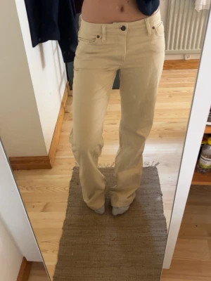 Beige raka jeans - Säljer ett par beige jeans med rak passform och låg midja. Jeansen har klassiska fem fickor och stängs med knapp. Materialet är denim och färgen är ljusbeige, perfekt för en clean och stilren look. STORLEK xs oxh jag är 165 som referens, dom är långa på mig och släpar i marken