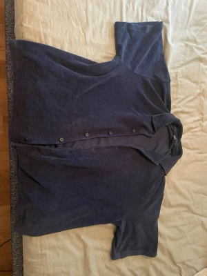 Mörkblå henley från Jack & Jones - Mörkblå henley från Jack & Jones Premium med korta ärmar och knappar längs bröstet. Skjortan är gjord i mjuk bomull och har en enkel, stilren design som passar perfekt till jeans eller shorts.