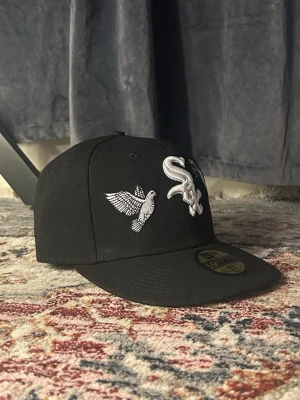 Svart keps från New Era - Snygg Svart keps från New Era med LA Dodgers-logga broderad i vitt framtill och World Series-märke på sidan. Klassisk flat brim och justerbar passform. Tillverkad i slitstark bomullsmix, perfekt för dig som gillar sportig streetstyle.