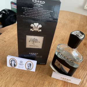 Creed Aventus Eau de Parfum - Creed Aventus Eau de Parfum i elegant glasflaska med svart och silverdetaljer. Flaskan har en unik form med svart kork och silveremblem på toppen. Kommer i lyxig svart förpackning med silverdetaljer och Creed-logga. En ikonisk doft för dig som vill sticka ut.