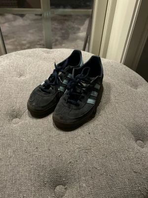 Adidas spezial mörkblå sneakers - Klassiska Adidas Samba sneakers i svart mocka med de ikoniska tre vita ränderna på sidan och mörk sula. Lågt skaft och snörning framtill. Perfekta för en sportig och stilren look. Jag har haft dessa skor i ca 1 år men inte såpass använda bara på sommaren lite vår och höst. Anledning till att jag säljer dem är för att jag har dels fått nya och de är för små