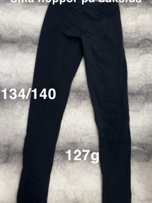 Träningstights från lindex - Säljer ett par svarta träningstights i stretchigt och mjukt material. De har en enkel, klassisk design med smal passform och resår i midjan. 🌸 Mindre fläckar. Mini noppor framförallt på baksida. Storlek 134/140