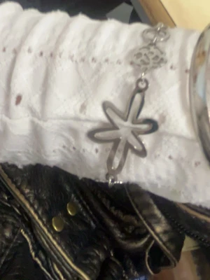 Silverfärgat armband med blomma - Stilrent armband i silverfärgad metall med en stor öppen blomformad detalj och en mindre blomma som dekoration. 