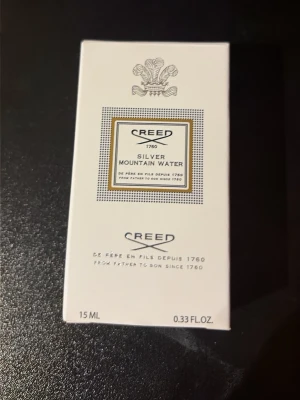 Creed Silver Mountain Water 15 ml - Lyxig parfym från Creed i doften Silver Mountain Water. Flaskan är vit med silverfärgad kork och har en elegant, stilren design. Förpackningen är vit med klassisk Creed-logga och detaljer i svart och silver. Innehåller 15 ml.
