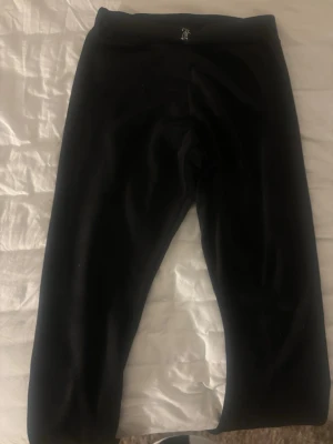 Svarta Juicy Couture mjukisbyxor - Säljer ett par klassiska svarta mjukisbyxor från Juicy Couture i mjuk velour. Byxorna har resår i midjan och texten 'Juicy' i glittriga stenar på baksidan. Perfekta för en chill och trendig look.