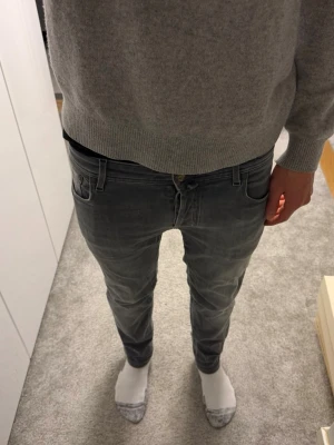 Jacob cohen jeans  - Snygga grå slim fit jeans från JACOB Cohen med klassisk femficksdesign och dragkedjegylf. Jeansen har en tvättad look och smal passform som sitter tajt längs benen. Perfekta för en stilren och avslappnad outfit.